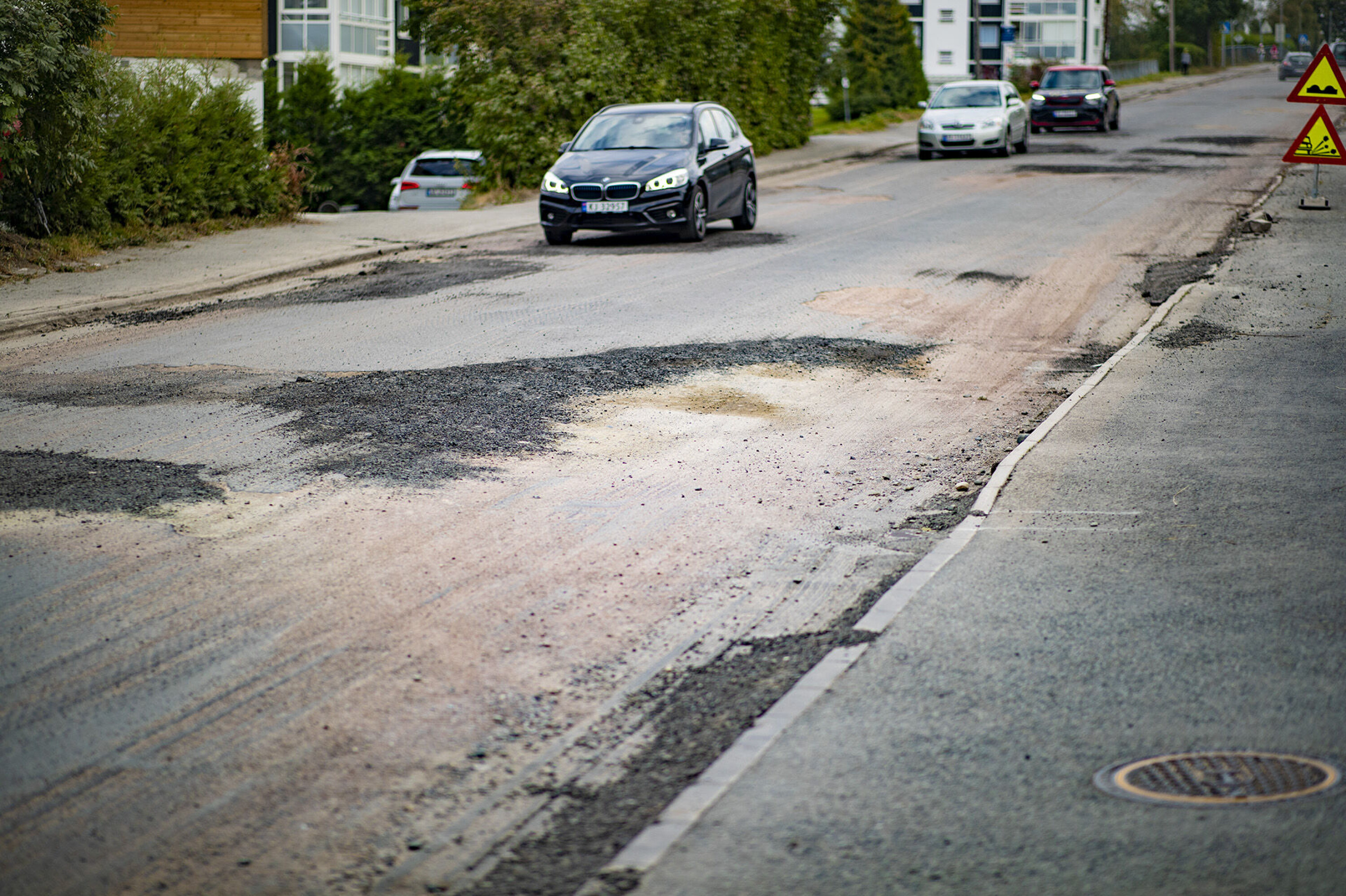 AUSTADVEIEN: Grus, dype hull, skarpe asfaltkanter og manuell dirigering preger veistrekningen for tusenvis av bilister, busser, og myke trafikanter.