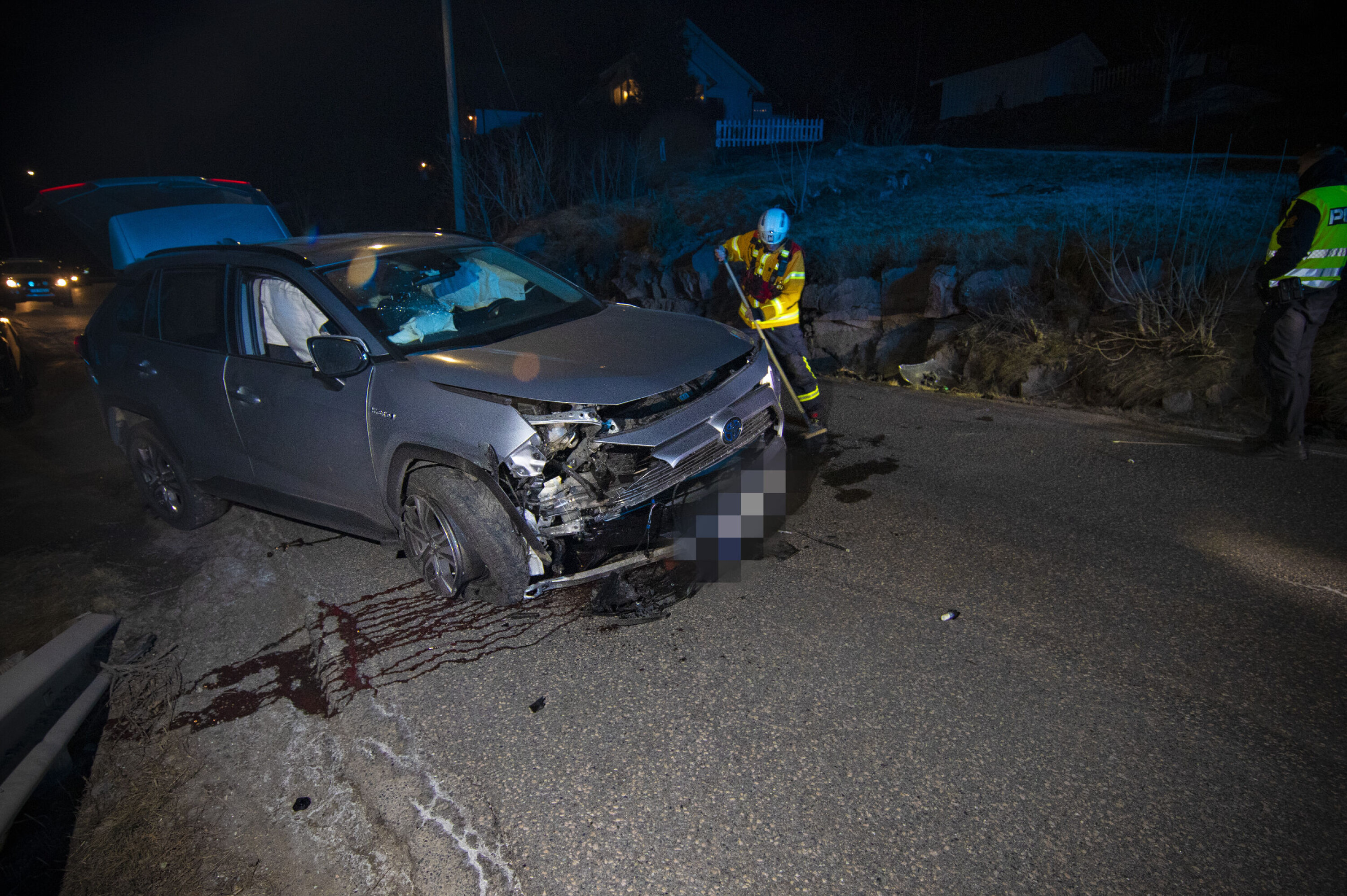 KRAFTIG SMELL: Bilen fikk store skader og alle airbagene løste ut i sammenstøtet med fjellveggen til høyre i bildet, hvor det ble liggende flere vrakdeler. Her har brannvesenet snudd bilen etter at den ble liggende på siden.
