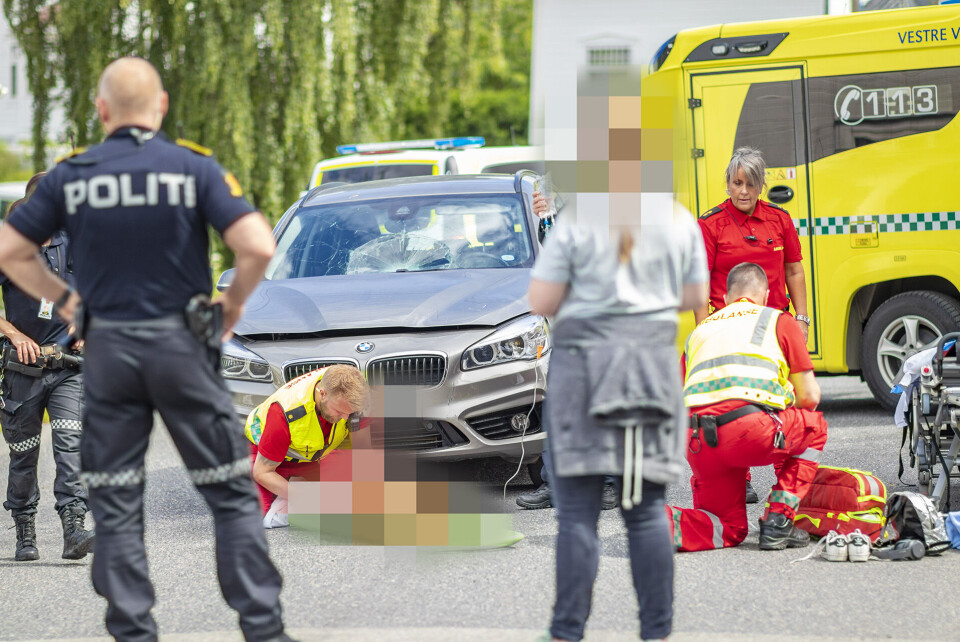 SKADD: Her jobber ambulansepersonell med jenta. Bilen i bakgrunnen fikk knust frontruta i sammenstøtet.