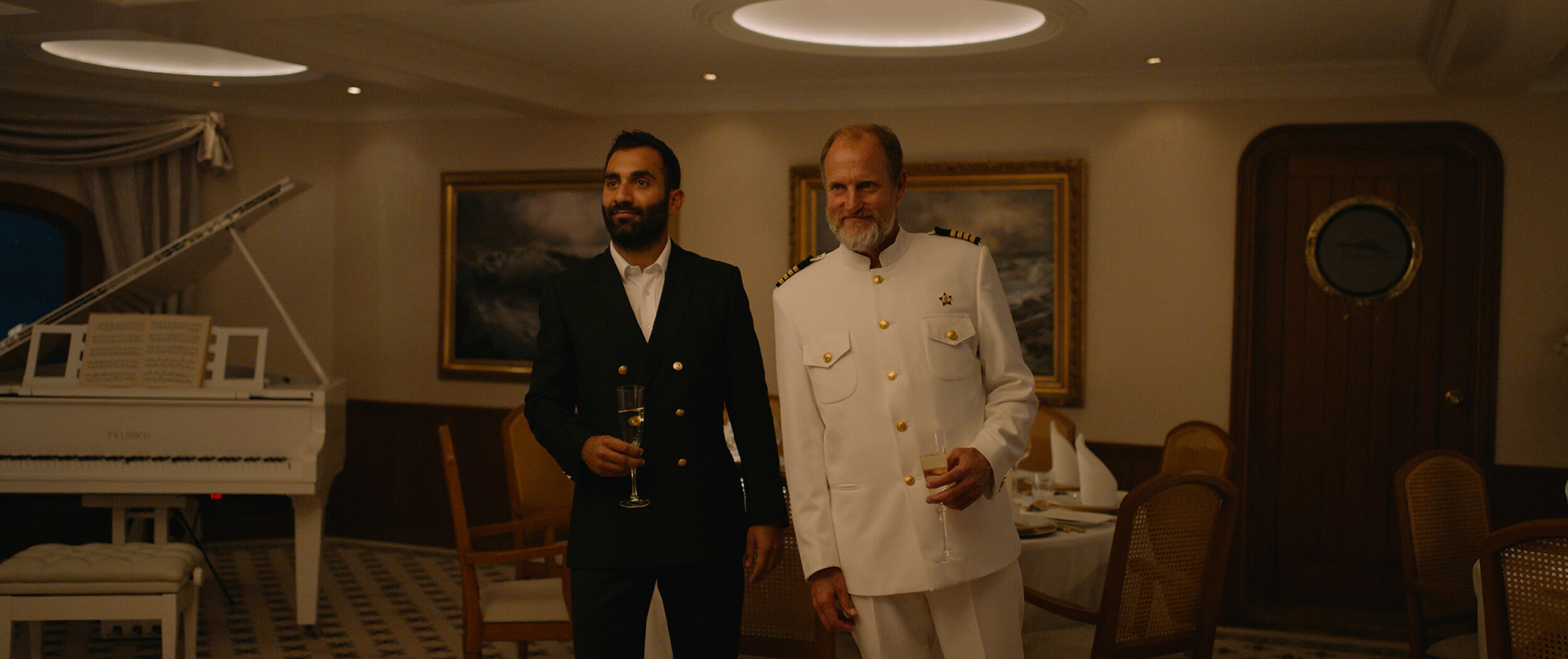 Styrmann (Arvin Kananian) og selveste Kapteinen (Woody Harrelson) velkommer sine gjester til en minneverdig aften