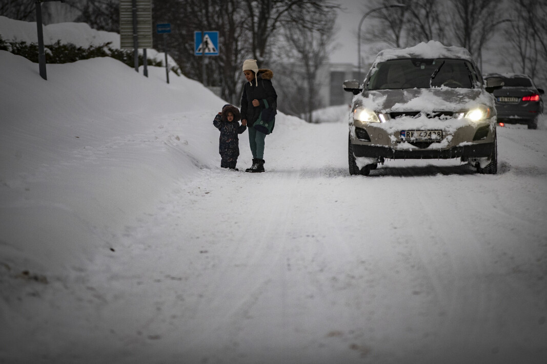 TVINGES UT I GATA: En ung mor og hennes barn på vei hjem ved en bussholdeplass i Austadveien fredag ettermiddag. En halvmeter snø på fortauet tvinger de myke trafikantene ut i veibanen.