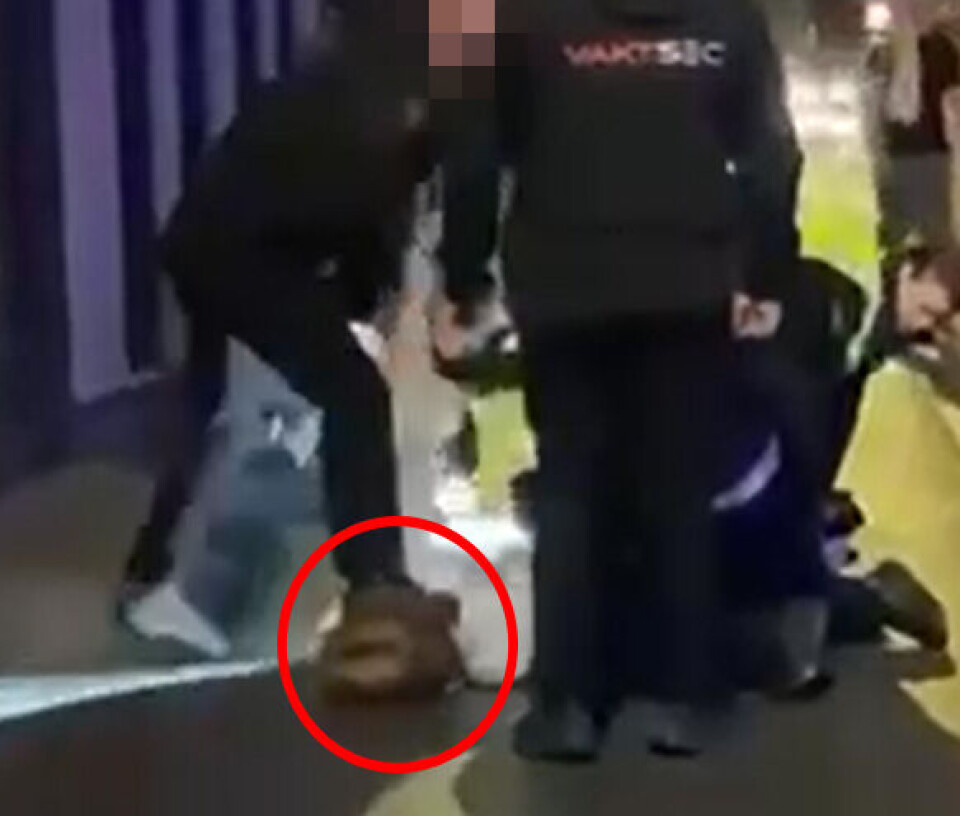 Dørvakten drar mannens arm opp mens han trykker vedkommendes hals/nakke ned i asfalten i flere sekunder